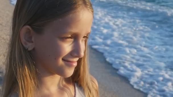 Gyermek játszik a strandon naplementében, Kölyök néz tengeri hullámok, Lány kilátás naplementekor — Stock videók