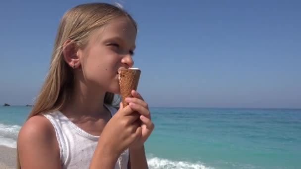 Дитину, їдять морозиво на пляжі на захід сонця, маленька дівчинка на березі моря влітку — стокове відео