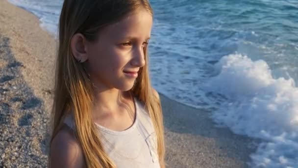 Kind spielt am Strand bei Sonnenuntergang, Kind beobachtet Meereswellen, Mädchenporträt an Land — Stockvideo