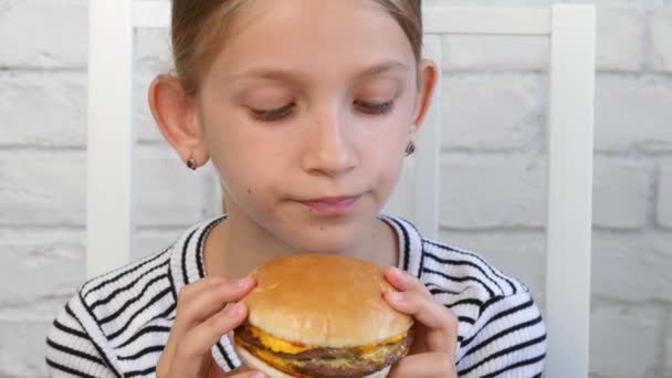 Criança comendo fast food, criança come hambúrguer no restaurante, menina bebendo suco — Vídeo de Stock