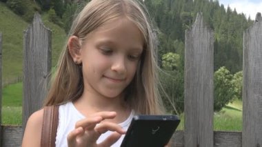 Smartphone Tablet, kız doğada rahatlatıcı açık, çocuk tarama oynayan çocuk