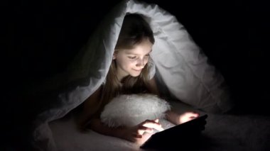 Tablet karanlık gecede, kız yatakta uyumuyor Internet tarama oynayan çocuk 