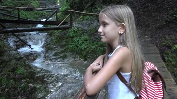 Niña en el puente en las montañas, Niña senderismo en la naturaleza, Niña mirando un río, Corriente — Vídeos de Stock