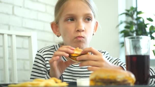 El niño come comida rápida, el niño come hamburguesa en el restaurante, la niña bebe jugo — Vídeo de stock