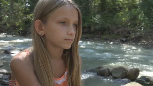 Печальный ребенок у реки, прекрасный ребенок, отдыхающий на природе, девочка в лесу, гора — стоковое видео
