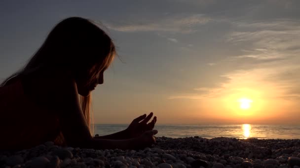 Copil pe plajă, copil care se joacă pe țărm în Apus de soare, fată care se uită la studierea pietricelelor — Videoclip de stoc