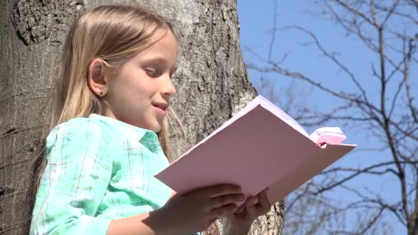 Barn läsa i träd Park, Skolflicka läser bok utomhus i naturen, uppfostrande — Stockvideo