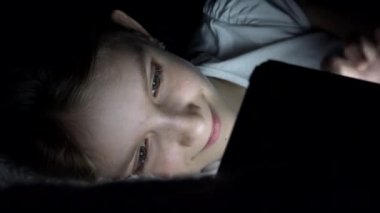 Tablet karanlık gecede, kız yatakta uyumuyor Internet tarama oynayan çocuk