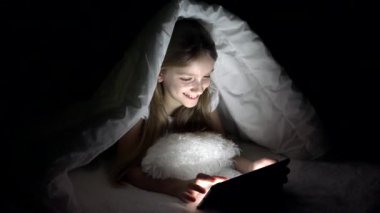 Tablet karanlık gecede, kız yatakta uyumuyor Internet tarama oynayan çocuk