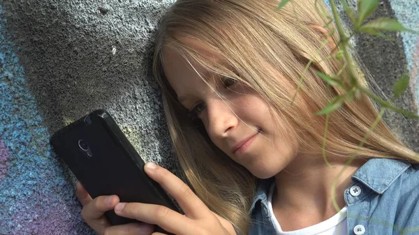 Niño usando Smartphone, Niño jugando en el teléfono inteligente, Chica al aire libre en el parque —  Fotos de Stock