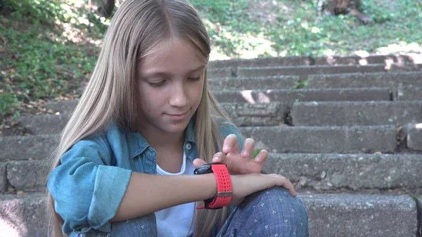 Relógio inteligente, criança usando Smartwatch ao ar livre no parque, criança jogando em Smartphone — Fotografia de Stock