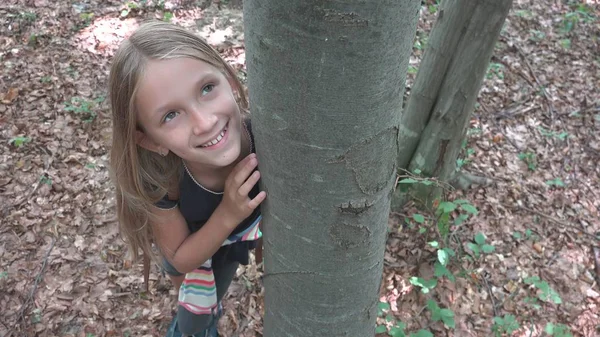 Kind im Wald, Kind spielt in der Natur, Mädchen im Abenteuer draußen hinter einem Baum — Stockfoto