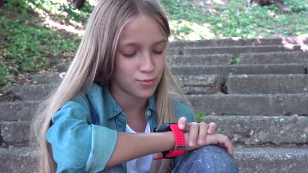 Smart Watch, barn som använder SmartWatch utomhus i parken, Kid Talking på smartphone — Stockvideo