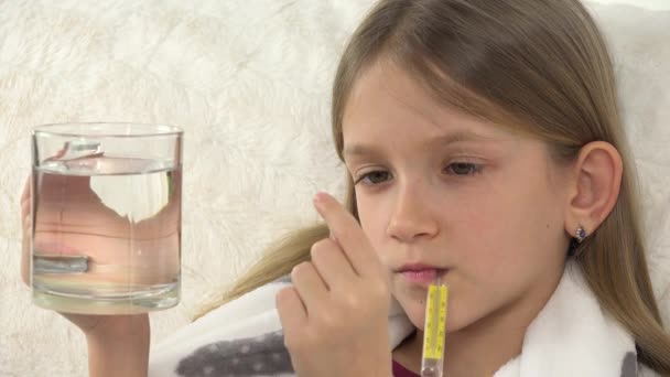 体温計で病気の子供 水で薬を飲む 子供の飲み物の丸薬 ソファ上の悲しい病気の女の子の顔 — ストック動画