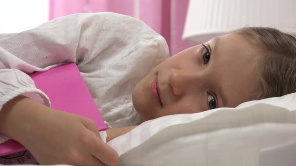 躺在床上不睡觉的忧心忡忡的孩子 躺在床上看书后醒悟的孩子 睡房里的女孩脸4K — 图库视频影像