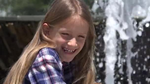 Детский портрет, смеющийся на открытом воздухе, играющий в парке ребенок, улыбающаяся девочка у фонтана летом — стоковое видео