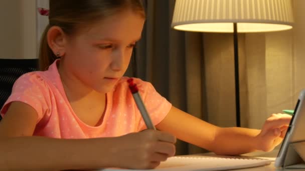 Kind maakt gebruik van Tablet Studeren, School Girl Writing Huiswerk in de nacht internetgebruik — Stockvideo