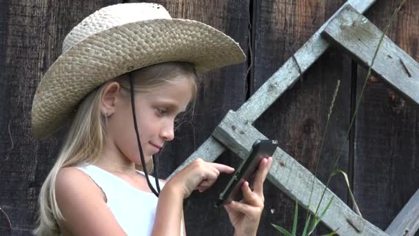 Kind spielt Tablet im Freien, Cowboy-Kind surft Smartphone, rustikales junges Mädchen sucht Internet Online — Stockvideo