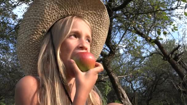 Kid jíst jablko, Dítě v sadu, Kid ochutnávka ovoce na stromě, Farmář dívka na vesnici — Stock video