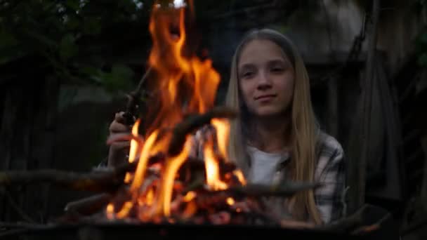 Kind spielt nachts am Lagerfeuer, Kind spielt mit Feuer in der Natur, Mädchen auf dem Land — Stockvideo
