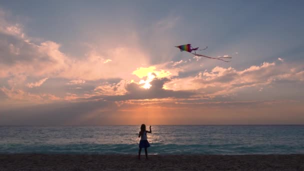 Kid leker på stranden på stranden, barn flygande drake vid solnedgången på havet, lycklig liten flicka på kustlinjen, Foreshore av skymningen — Stockvideo