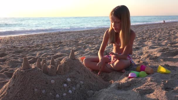 Kid Building Castle a strandon naplementekor, gyermek játszik homok a tengerparton, szőke lány játszik a tengeren — Stock videók