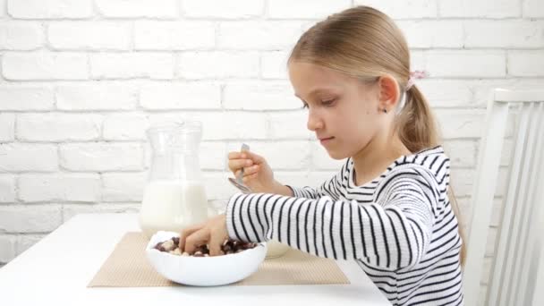 Gyerek eszik tej és gabonafélék reggelinél, gyermek a konyhában, szőke tini lány kóstoló egészséges ételek étkezés, Táplálkozás — Stock videók