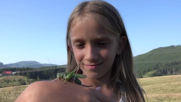 Ребенок с кузнечиком на поле в горах, ребенок, играющий с насекомыми на лугу, сельская девочка — стоковое видео