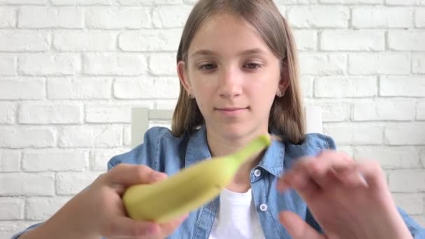 Ребенок ест банан, ребенок ест фрукты, молодая девушка за завтраком на кухне — стоковое видео