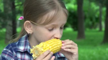 Çocuk parkta haşlanmış mısır yiyor, Aç Kız sağlıklı abur cubur yiyor, Genç Sarışın Çocuk doğada dinleniyor.