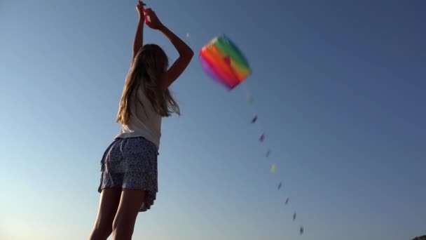 Παιδί που παίζει ιπτάμενο χαρταετό στην παραλία στο ηλιοβασίλεμα, χαρούμενο κοριτσάκι στην ακτογραμμή στις καλοκαιρινές διακοπές — Αρχείο Βίντεο