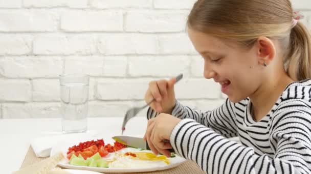 Kid äter frukost i köket, barn äter stekta ägg, tonåring flicka njuter av grönsaker, grönska hälsosam mat — Stockvideo