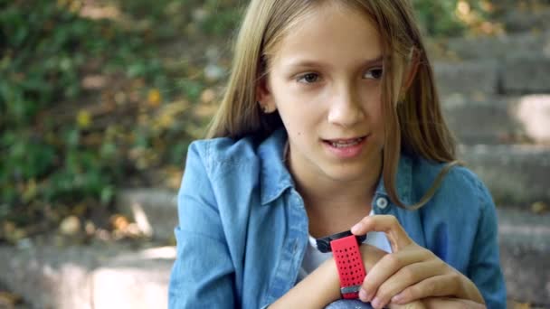 Chico hablando en Smartwatch en el parque, Niño usando un teléfono inteligente, Chica jugando en el dispositivo, Niños navegando por Internet en el reloj inteligente — Vídeo de stock