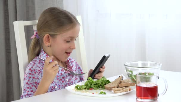 Child Eating Eggs, Lettuce, Kid Playing at Smartphone, Browsing Internet in Kitchen, Girl Texting on Touchscreen Tablet, Devices — Stock Video