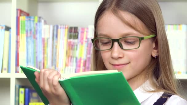 Barn läser en bok, barn läser en pedagogisk berättelse i klassrummet, student flicka studerar i skolbiblioteket, barn utbildning — Stockvideo