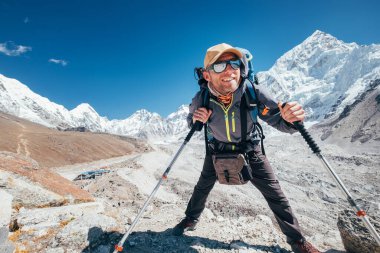 Nuptse 7861 m zirvesinde gülümseyen Yürüyüşçü adam portresi ve yürüyüş direkleri ile Gorak shep yerleşim geçmişi, güneş gözlüklerini koruyan UV. Everest Ana Kampı 'nın yürüyüş rotası boyunca dağdan keyif alıyor..