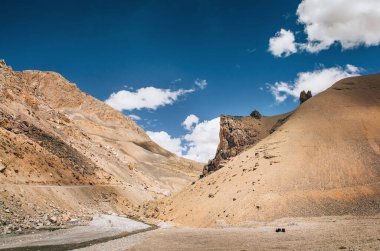 Sonsuz Leh-Manali yolu üzerindeki resim gibi dağ manzarası. Beyaz bulutlu mavi gökyüzü ve cansız çöl kayalık dağları. Uzak seyahat hedefleri konsept resmi.