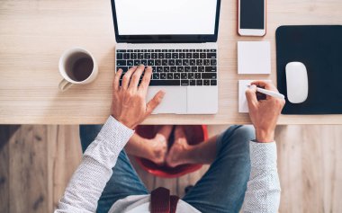 Çizgi roman modern ofis masa manzarası. İşadamı dizüstü bilgisayarda klavye kullanıyor, bilgisayar faresi kullanıyor ve ayakları masanın altında süzülüyor. Dünya çapında karantina zaman kavramında mesafe çalışması.
