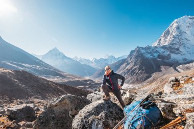 Everest Memorial, Chukpi Lhara, Nepal 'deki Everest Ana Kamp rotasında gülümseyen ve poz veren genç bir gezgin kadın. Ama Dablam Dağı 6812 metre arkaplanda. Etkin tatil konsepti resmi.