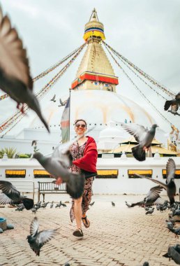 Güzel dişiler samimi bir şekilde gülümsüyor ve güvercinlerin arasından Nepal 'in en büyük küresel durgunluğu olan Boudhanath Stupa ile birlikte geçiyor. Dünya konsept resmini gezmek.