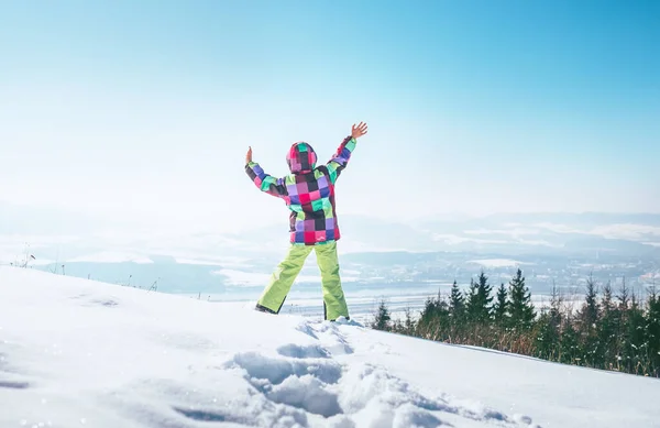 街の景色を眺めながら深い雪の丘の上をジャンプする幸せな女の子 — ストック写真