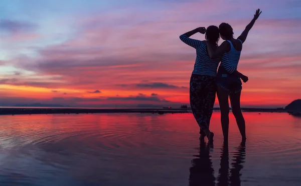 Две Девушки Обнимаются Наслаждаются Розовым Розовым Закатным Небом Морском Пляже — стоковое фото