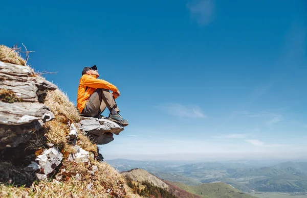 斯洛伐克马拉法特拉山脉 身着鲜艳的橙色夹克 头戴棒球帽 戴着太阳镜 坐在岩石悬崖上 享受着绿谷的美景 活跃人士与欧洲旅游概念形象 — 图库照片