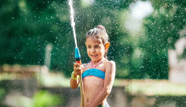 可爱的小女孩用软管给自己浇上了水 使炎热的夏天充满了雨的乐趣 粗心大意的童年概念形象 — 图库照片