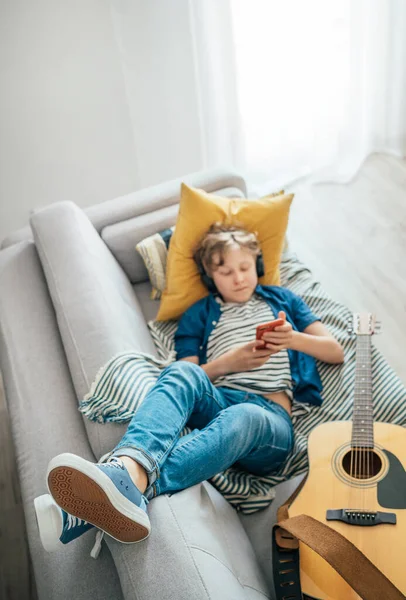 Niño Preadolescente Acostado Con Guitarra Sofá Acogedor Vestidos Vaqueros Casuales — Foto de Stock