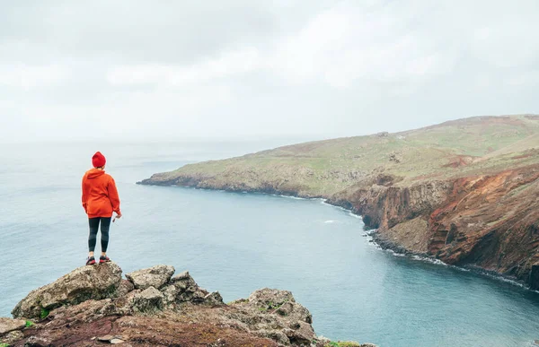 葡萄牙马德拉岛最东端的Ponta San Lourenco半岛 小径女运动员身穿橙色运动衫 头戴红帽 躺在悬崖上 — 图库照片