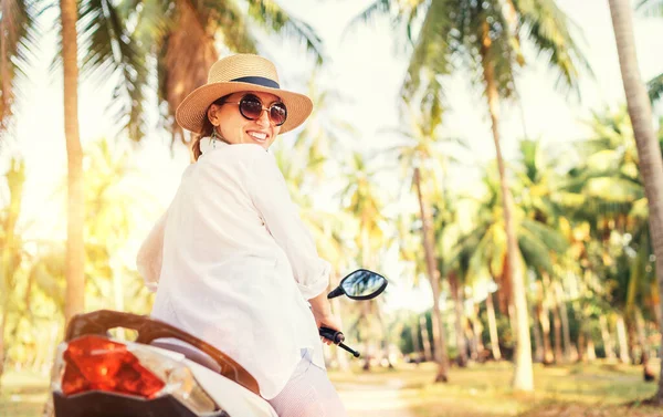 戴着草帽和太阳镜的快乐微笑的女人骑着摩托车站在树下 漫不经心地计算度假时间的概念形象 — 图库照片