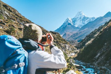 Genç gezgin kadın, yüksek rakım iklimlendirme yürüyüşü sırasında fotoğraf çekiyor. Everest Merkez Kampı 'nın yürüyüş rotası, Nepal. Etkin manzara fotoğrafçısı tatilleri konsept resmi.
