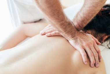 Masörün erkek elleri, genç kadın vücut masajı sırasında Scapula bölgesinde masaj manipülasyonları yapıyor..