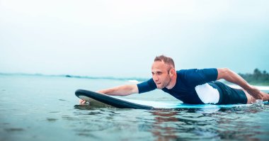 Adam sörf tahtasında sıraya dizilmiş. Etkin tatil harcama kavramı. 